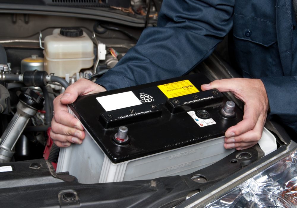 Auto mechanic replacing car battery